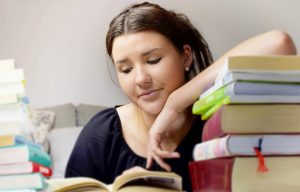 Teenage Girl studying for exam - looking at text books with worried face
