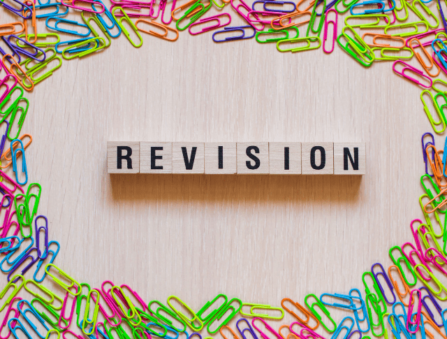 The word 'Revision' spelt in wooden blocks surrounded by colourful paperclips