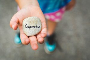 Child holding stone that says 'cooperation'