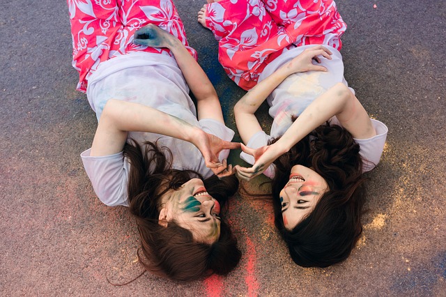 two girls lying on ground making heart shapes with their hands