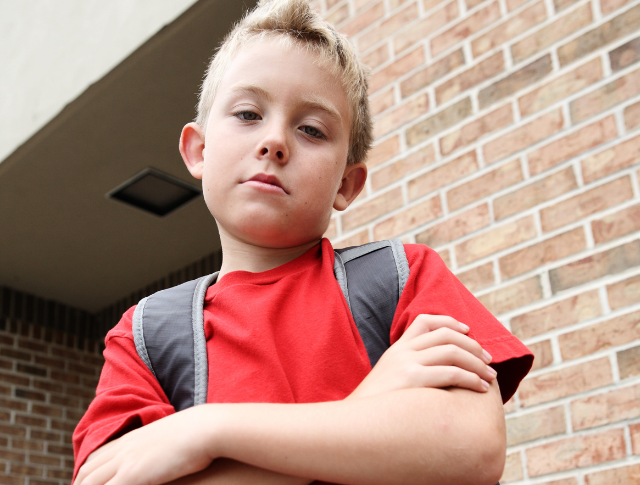 boy scowling with arms folded looking aggressive