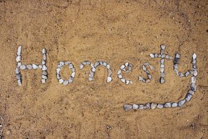 The word honesty written in pebbles in sand