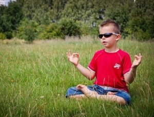 Young boy sitting cross-legged on grass meditating