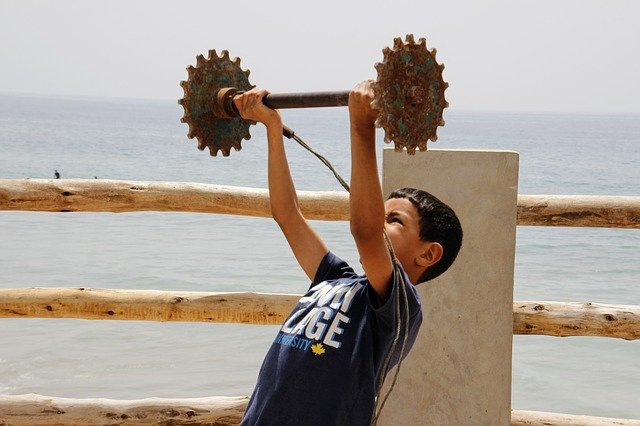 Boy Lifting Weights by Ocean