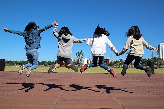 4 girls holding hands and jumping into the air