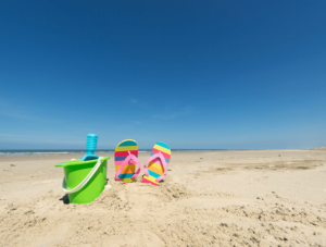 bucket and spade and kids flip flops on the beach