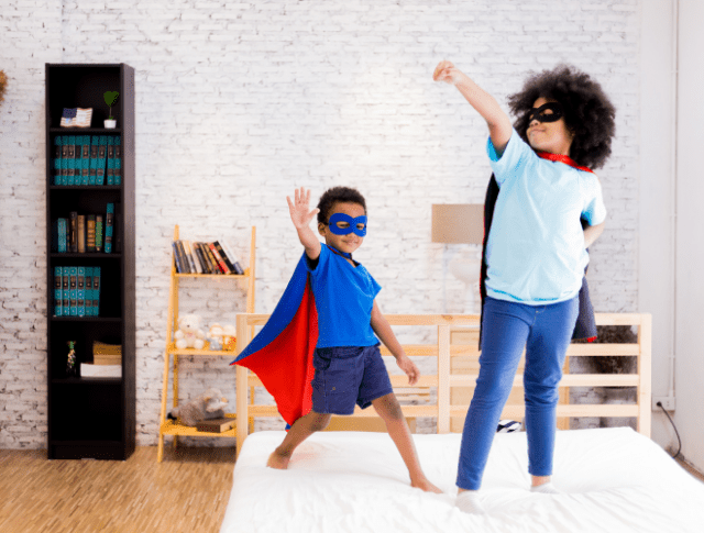 happy and confident young boy and girl playing superhero dress up