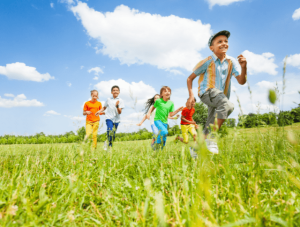 happy kids playing and running through field in summer