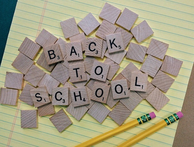 'Back to School' spelled on scrabble tiles on top of notebook and pencils