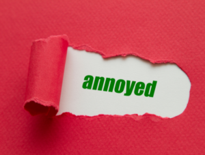 Torn red paper revealing the word 'annoyed'