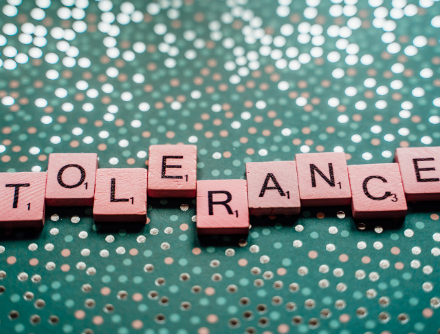 scrabble tiles spelling the word Tolerance, with glittery background