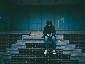 Boy sitting alone on a wall looking sad