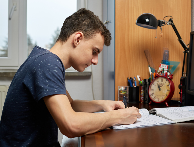 Teenage boy sitting at desk doing homework