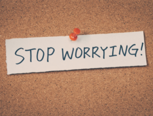 'Stop Worrying' written on a piece of paper and pinned to a cork board