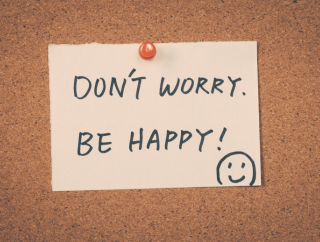 'Don't worry be happy' written on a piece of paper pinned to a cork board