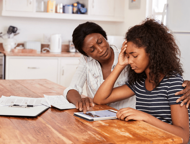 Mother helping stressed teenage daughter with homework